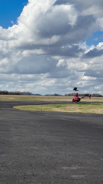 R22 on field with UH-60 departing behind it