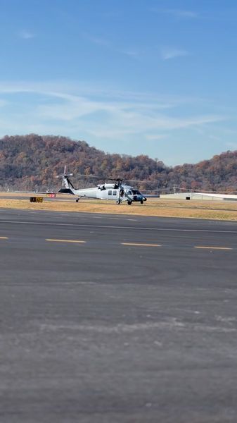 Grey UH-60 on runway with fall foliage hills