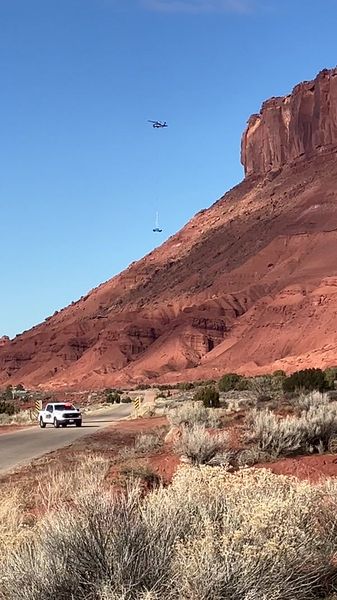 Helicopter with sling load over Moab canyon