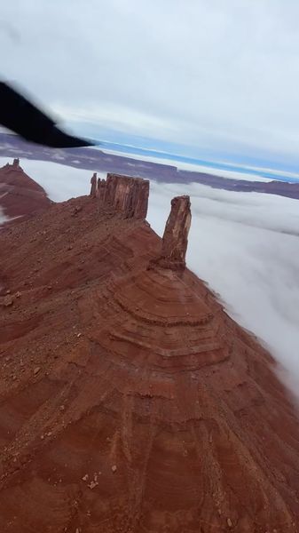 Red rock formations piercing through cloud layer